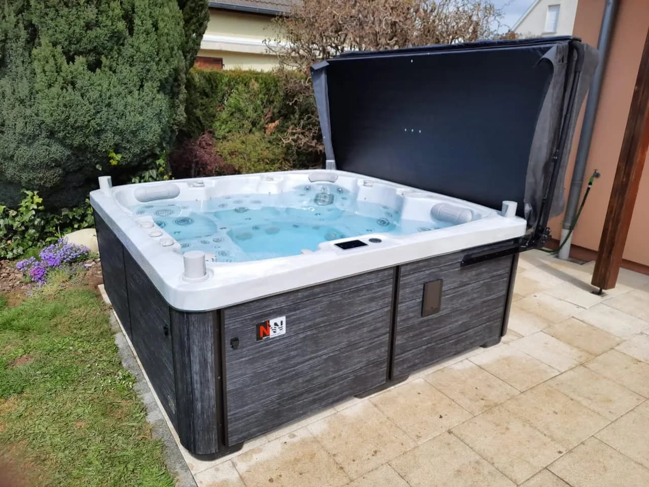 Installation d'un spa Sølveijg Full option à Heimsbrunn, sur une terrasse dallée, lève-couverture