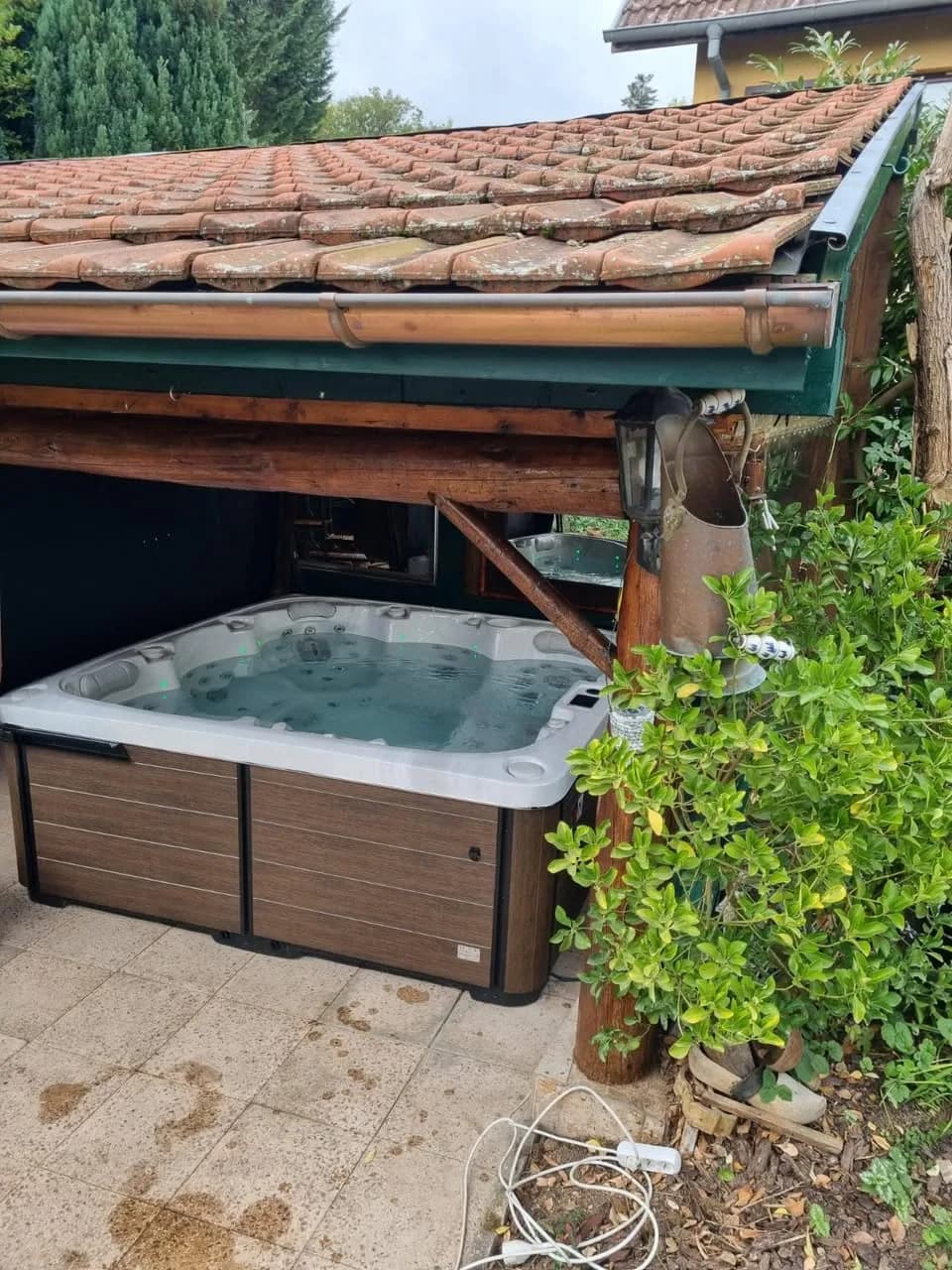 Installation d'un spa Sølveijg Full option à Jungholtz, sous un auvent couvert de tuiles