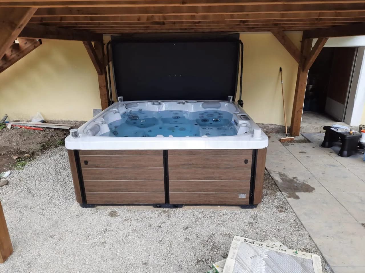 Installation d'un spa Sølveijg Full option à Pfastatt, sous un abri en bois, tablier couleur bois