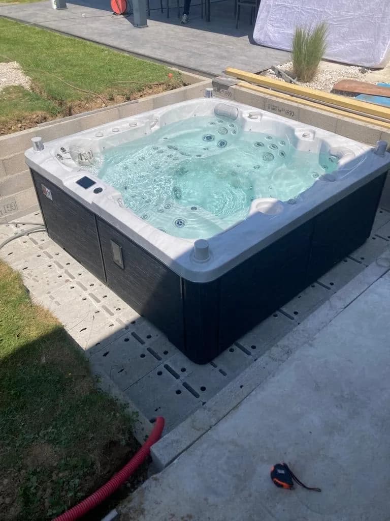 Installation d'un spa Sølveijg Full option à Ruy-Montceau, sur une dalle en bordure de pelouse