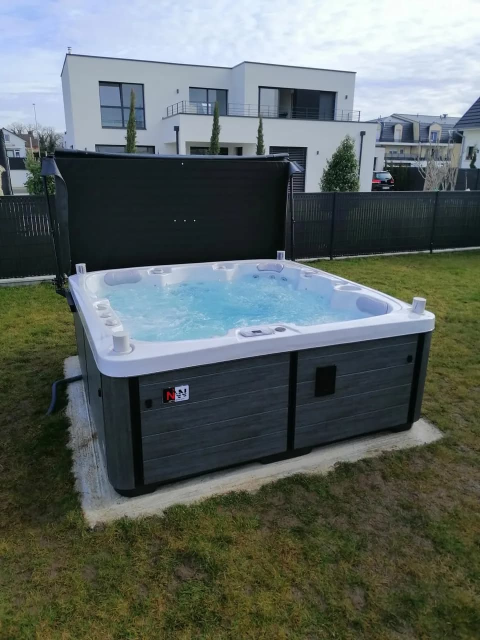 Installation d'un spa Sølveijg Full option à Saint-Louis, sur une dalle au bord d'une pelouse