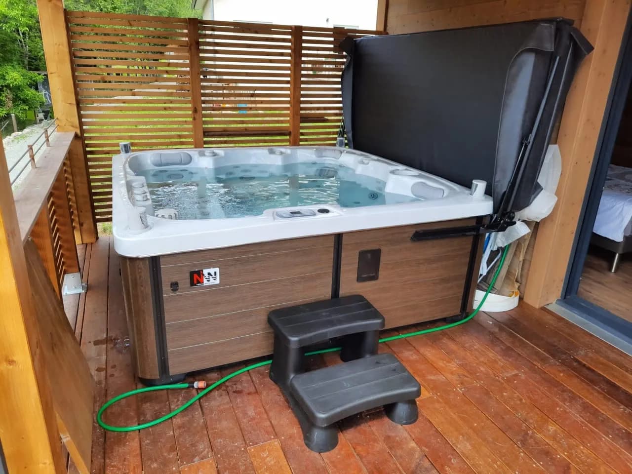 Installation d'un spa Sølveijg Full option à Sickert, sur une terrasse en bois couverte, marchepied