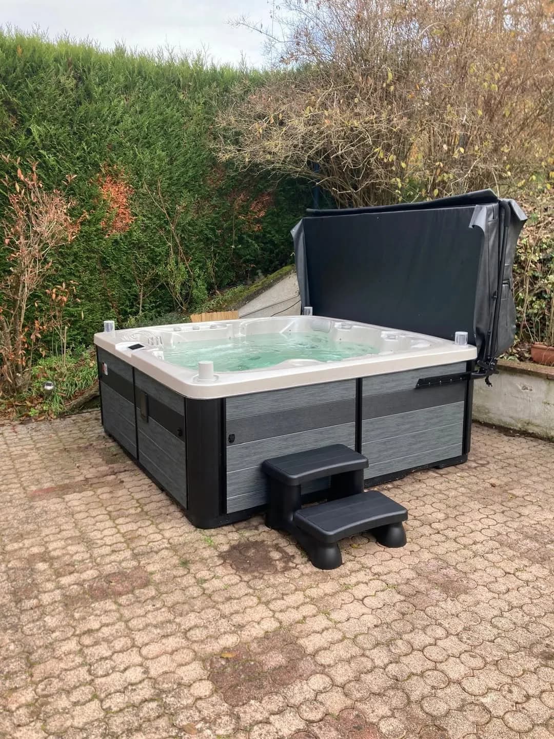 Installation d'un spa Sølveijg Full option à Soultzbach-les-Bains, sur une cour pavée, couverture relevée