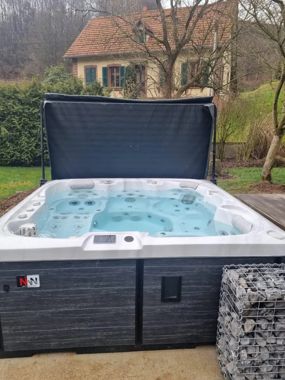 Installation d'un spa Sølveijg à Oberbronn, en bordure de pelouse, vue sur les collines