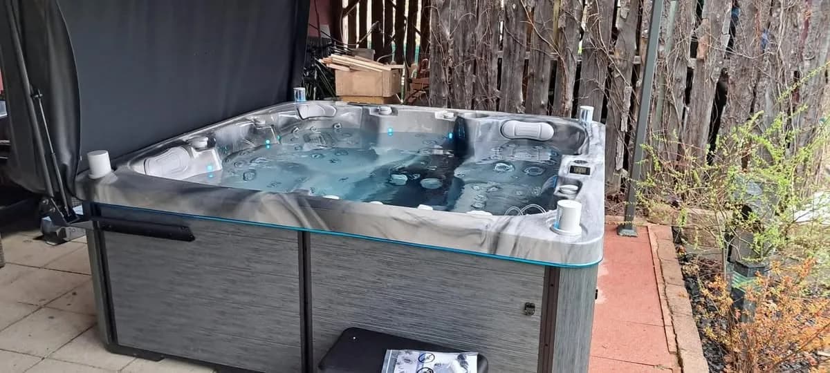 Installation d'un spa Sølveijg à Riespach, sur une terrasse devant une palissade en bois
