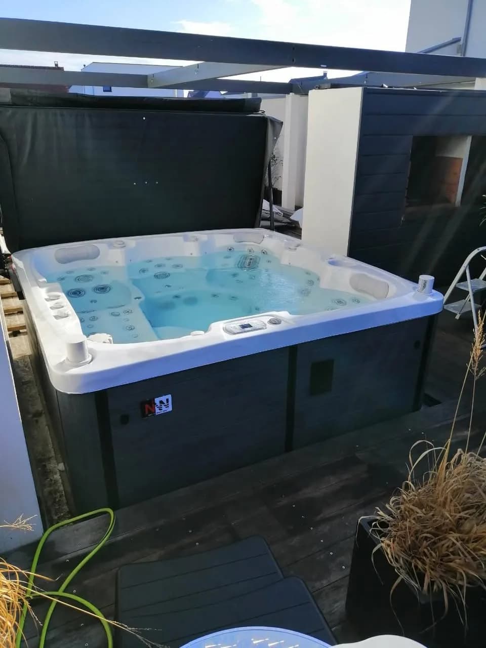 Installation d'un spa Sølveijg à Rustenhart, sur une terrasse en bois, lève-couverture