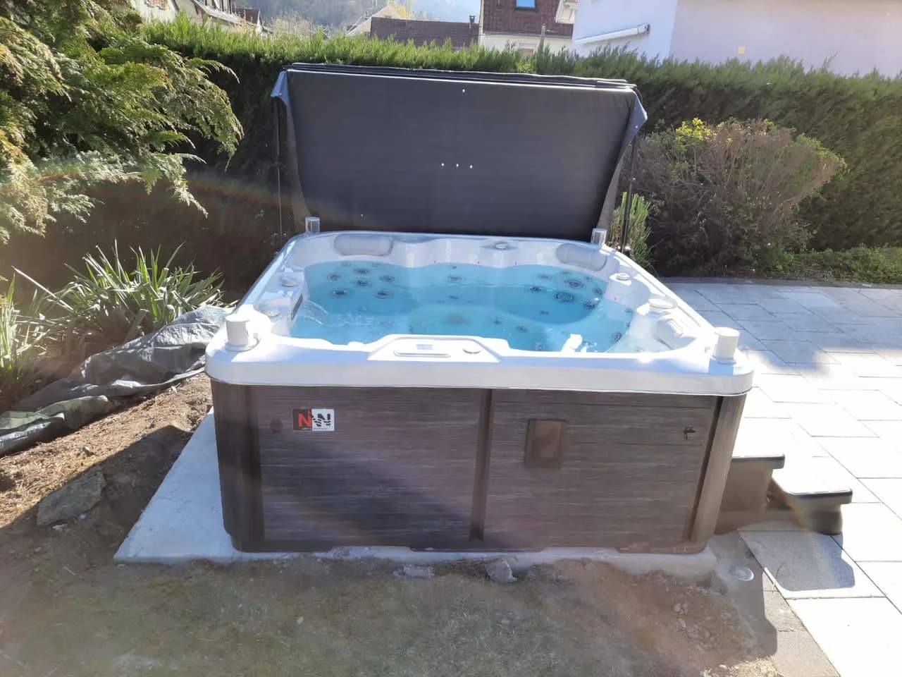 Installation d'un spa Sørrana Full option à Buhl, sur une dalle dans un jardin, lève-couverture