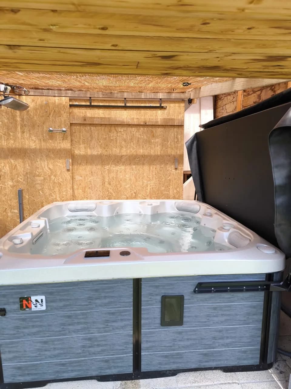Installation d'un spa Sørrana à Pair-et-Grandrupt, sous un abri à plafond en bois