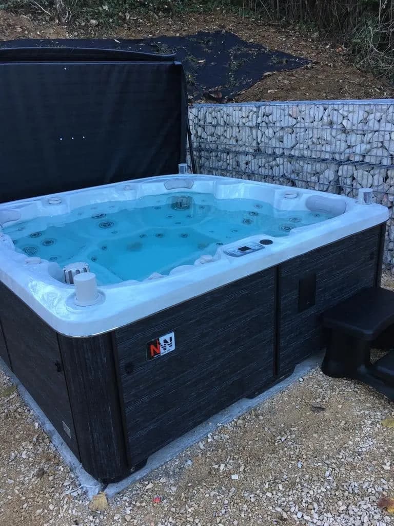 Installation d'un spa Søvik Full option à Magny-lès-Villers, sur du gravier devant un mur en gabions