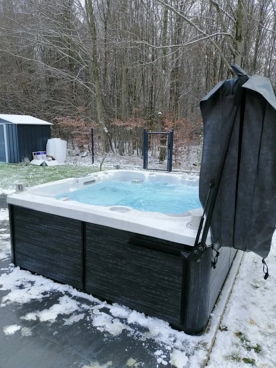 Installation d'un spa Søvik Full option à Seppois-le-Haut, dans un jardin enneigé, lève-couverture