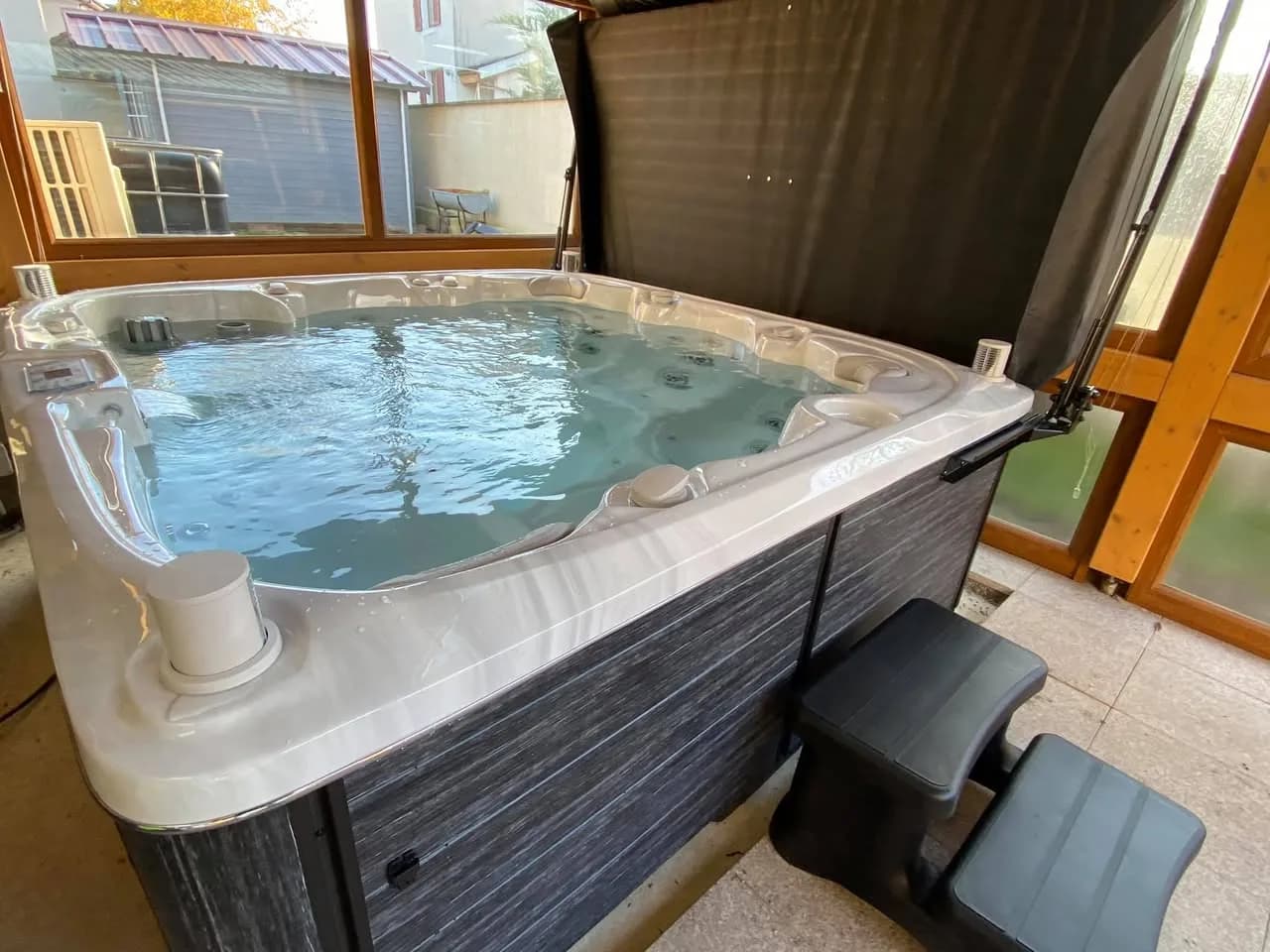 Installation d'un spa Søvik Full option à Wittelsheim, sous une véranda en bois, avec marchepied