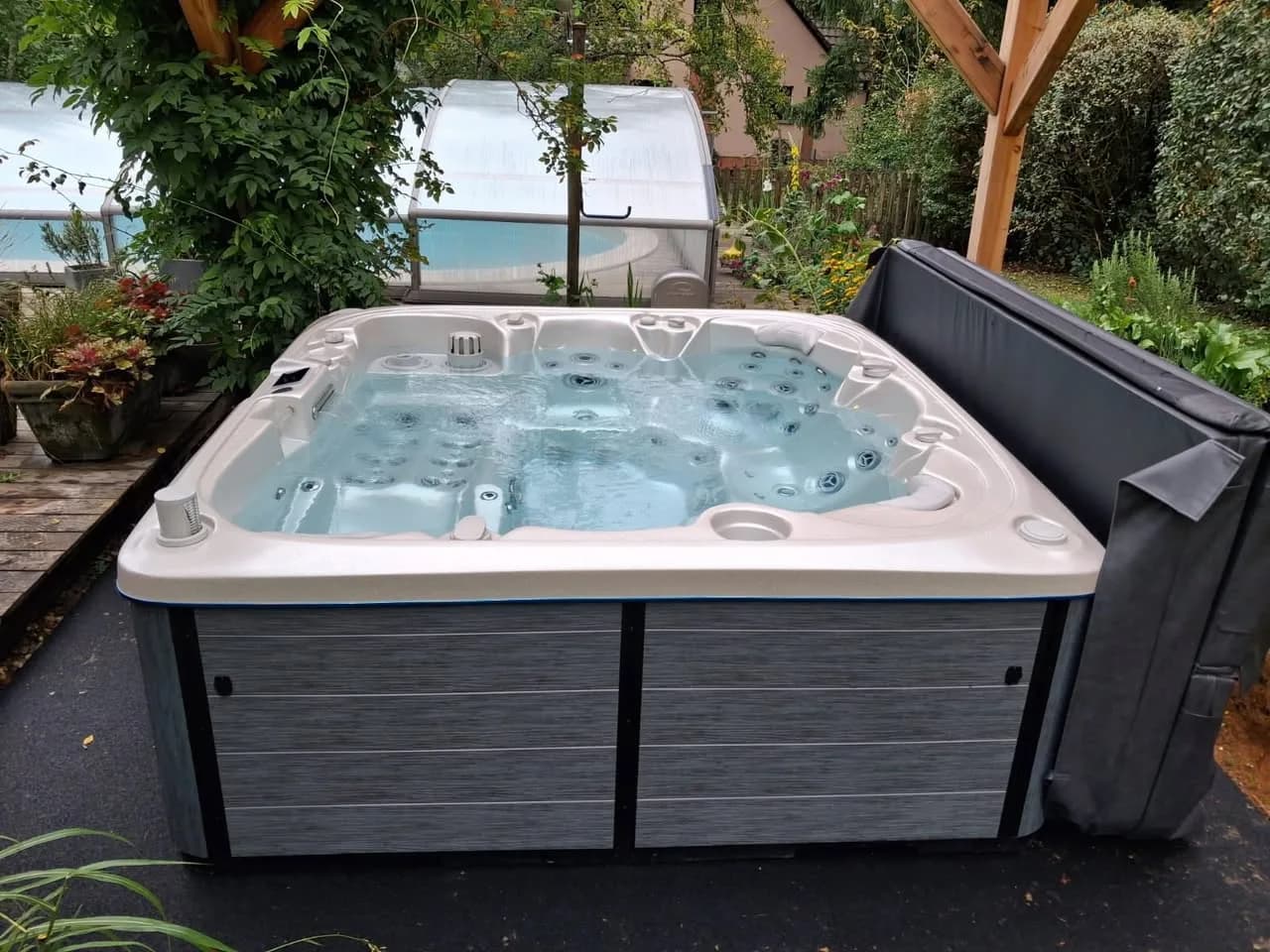 Installation d'un spa Søvik à Osenbach, sous une pergola en bois dans un jardin fleuri
