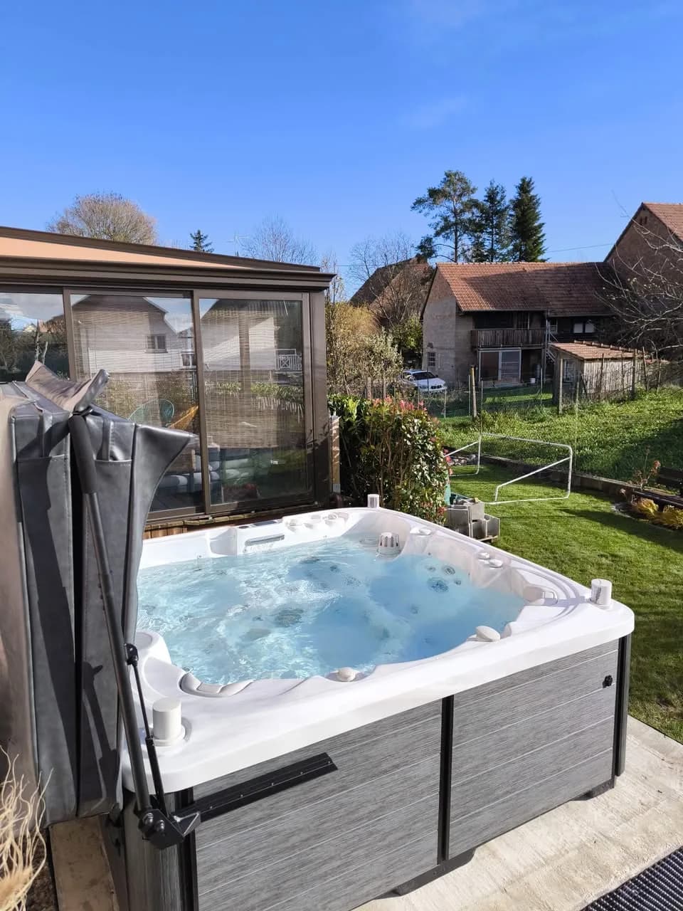Installation d'un spa Søvik à Schwenheim, dans le jardin, couverture relevée