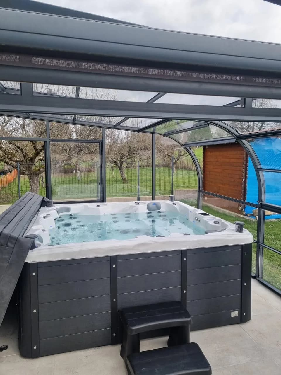 Installation d'un spa Sydney à Épeugney, sous un abri vitré, marchepied