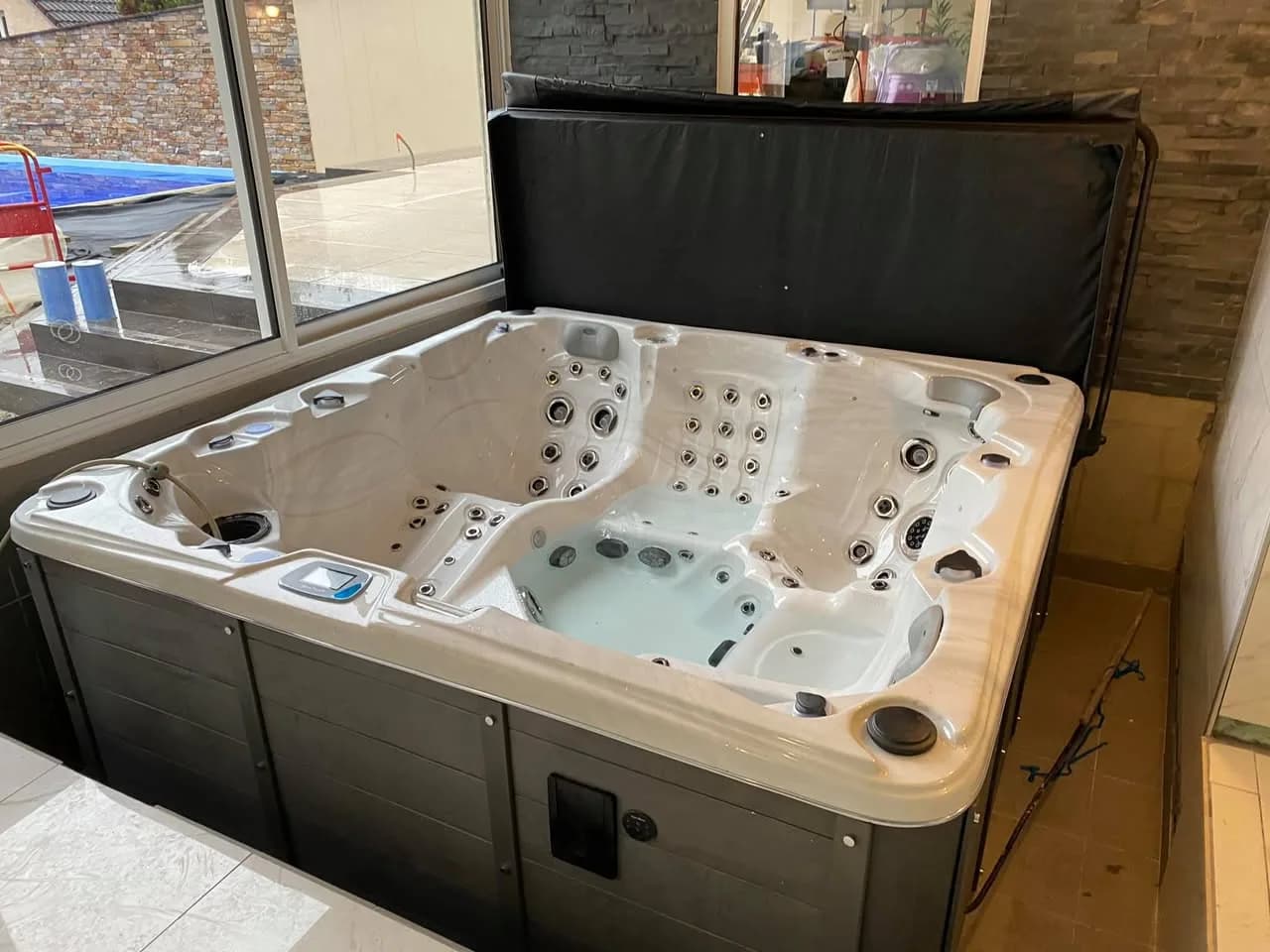 Installation d'un spa Sydney Full option à Baume-les-Dames, dans une pièce vitrée, avec lève-couverture