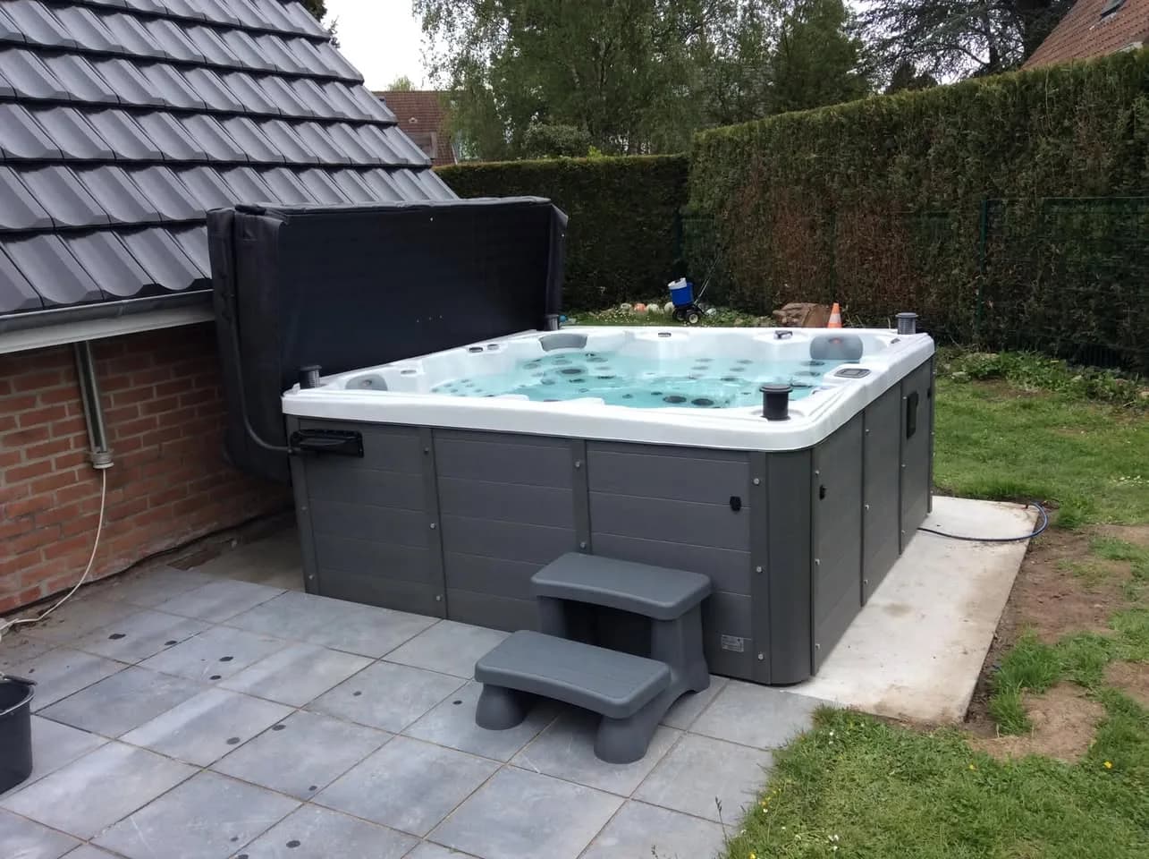 Installation d'un spa Sydney Full option en Belgique, sur une dalle carrelée en bordure de pelouse