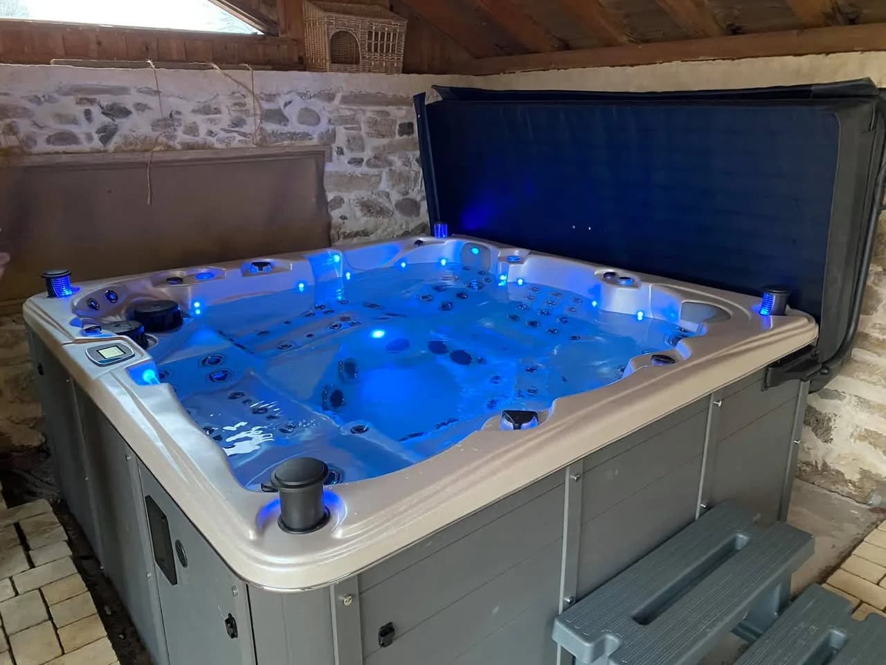Installation d'un spa Sydney Full option à Gildwiller, contre un mur de pierre, éclairage LED