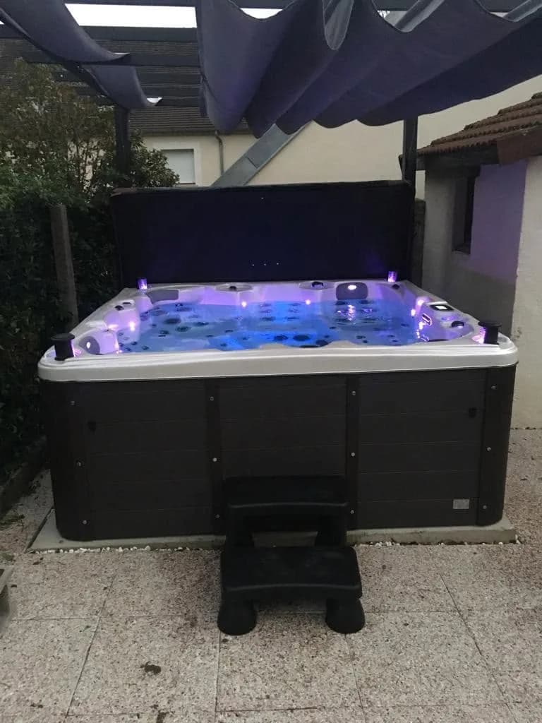 Installation d'un spa Sydney Full option à Gland, sous une toile tendue, éclairage LED allumé