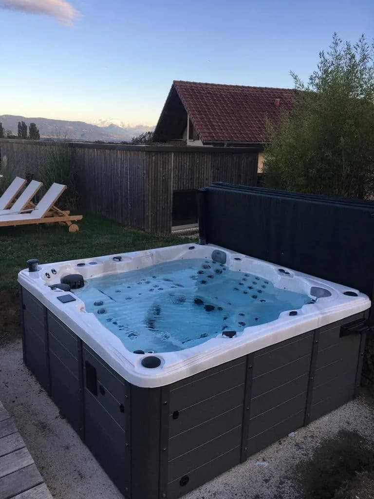 Installation d'un spa Sydney Full option à Grilly, sur une terrasse en bois près d'une piscine