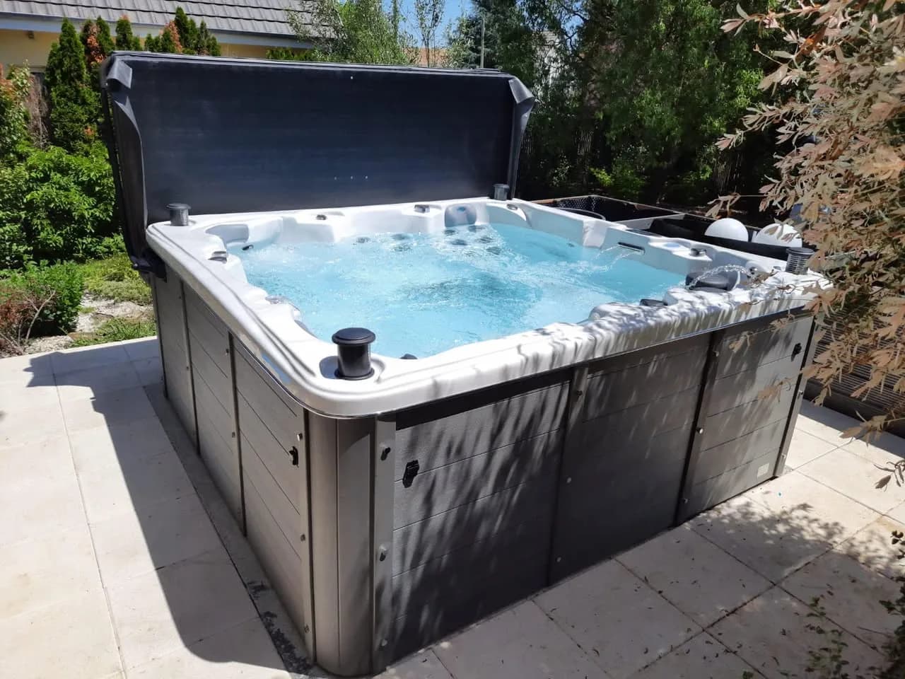 Installation d'un spa Sydney Full option à Ranspach-le-Bas, sur une dalle dans un jardin, lève-couverture