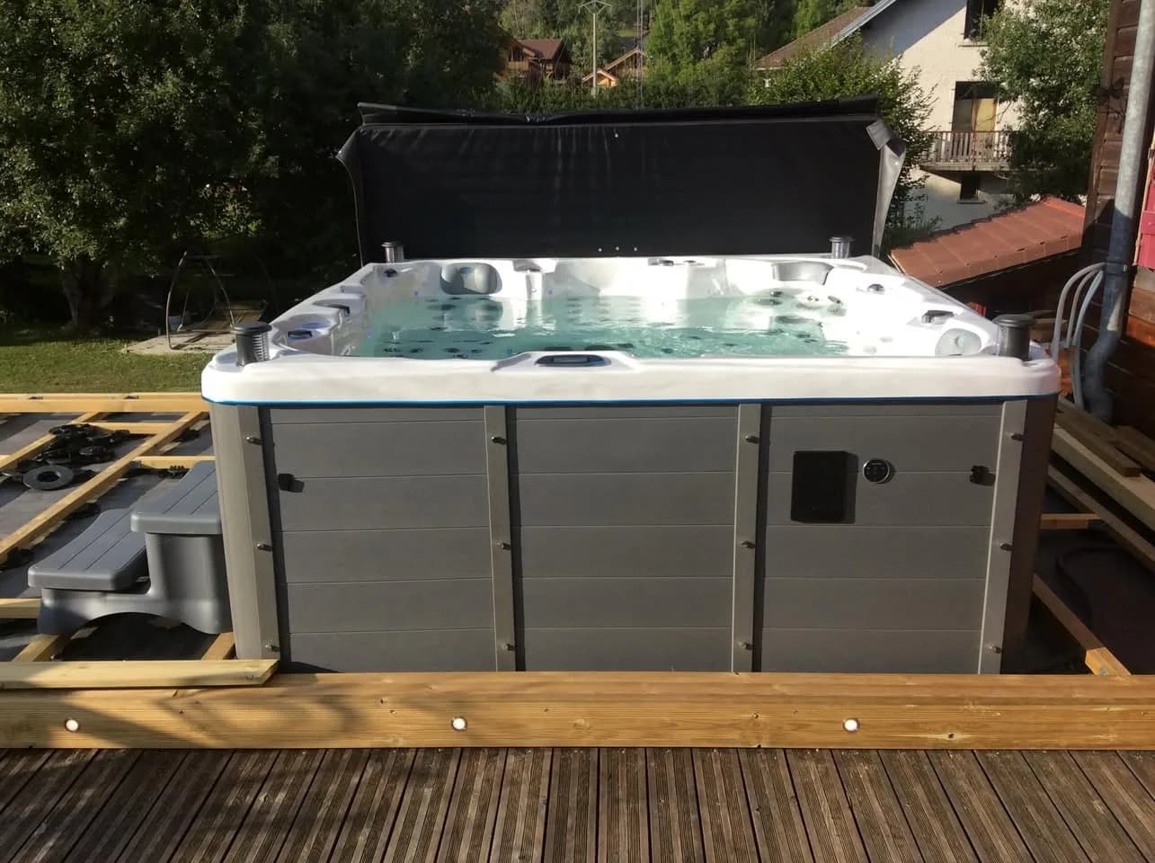 Installation d'un spa Sydney à Morbier, sur une terrasse en bois, lève-couverture