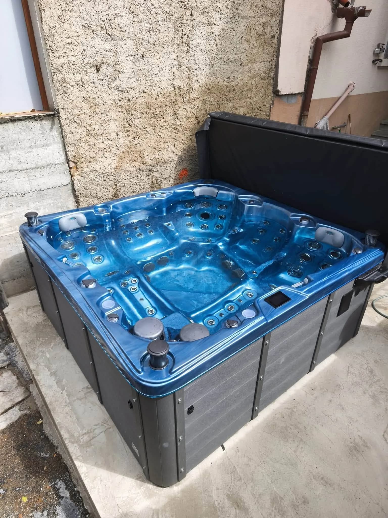 Installation d'un spa Sydney à Waldighoffen, cuve bleu marbré contre un mur en pierre
