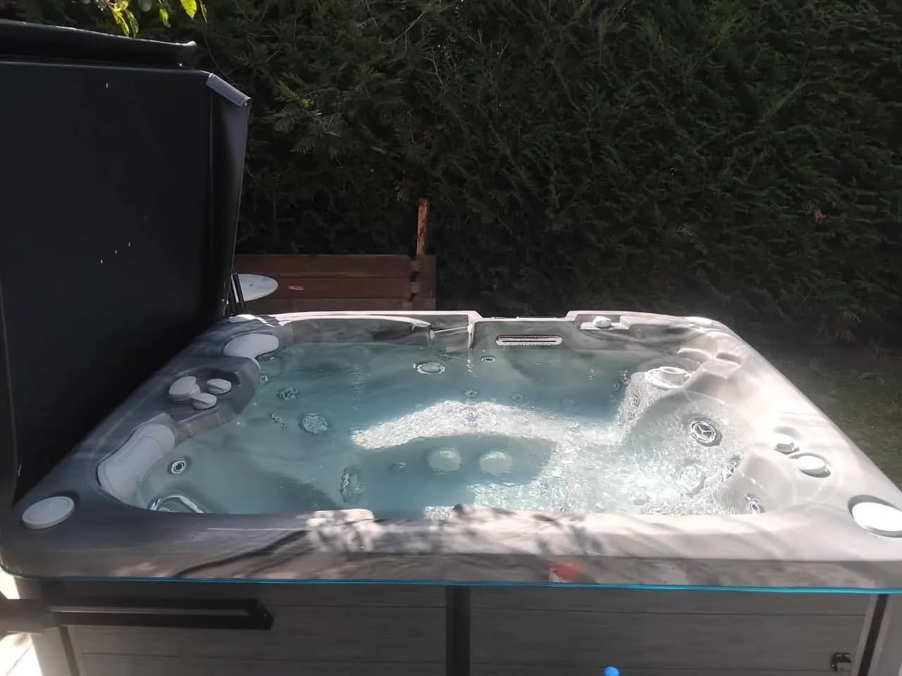 Installation d'un spa Tønsberg à Buschwiller, dans un jardin devant une haie