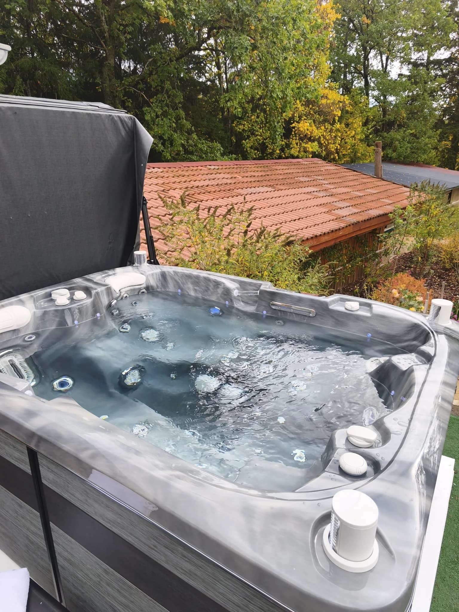 Installation d'un spa Tønsberg à Champenay, Plaine, cuve grise marbrée, couverture relevée, jardin arboré