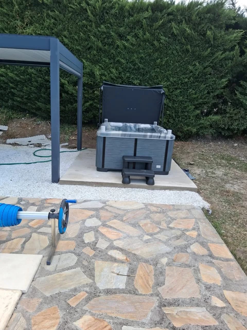 Installation d'un spa Tønsberg Full option à Dallet, sur une dalle devant une haie