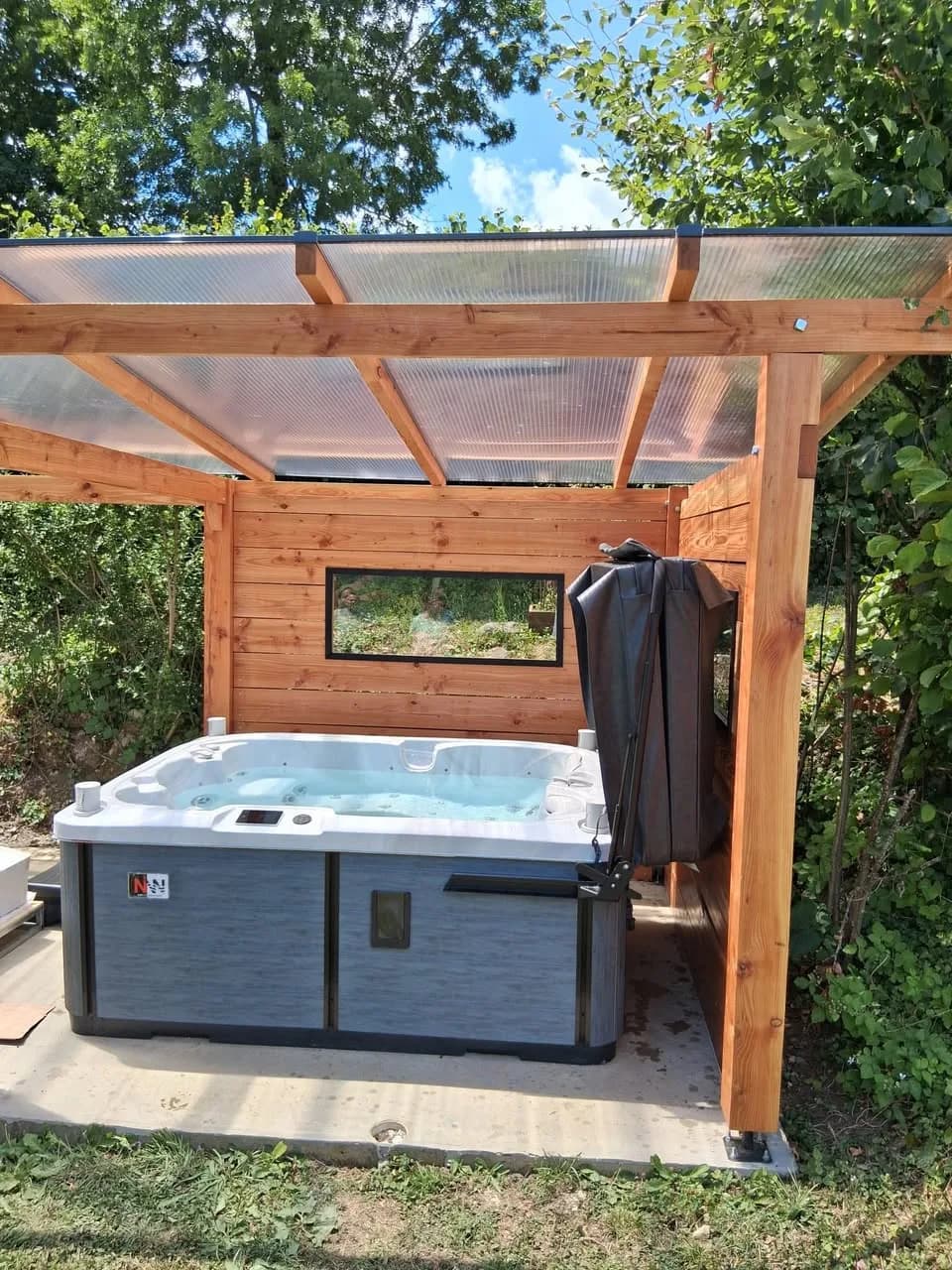 Installation d'un spa Tønsberg Full option en Isère, sous une pergola en bois à toit translucide
