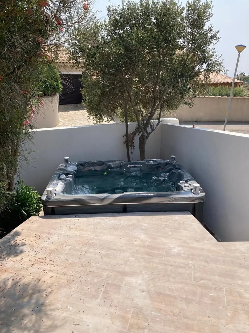Installation d'un spa Tønsberg Full option à Sausset-les-Pins, dans un angle de terrasse à côté d'un olivier
