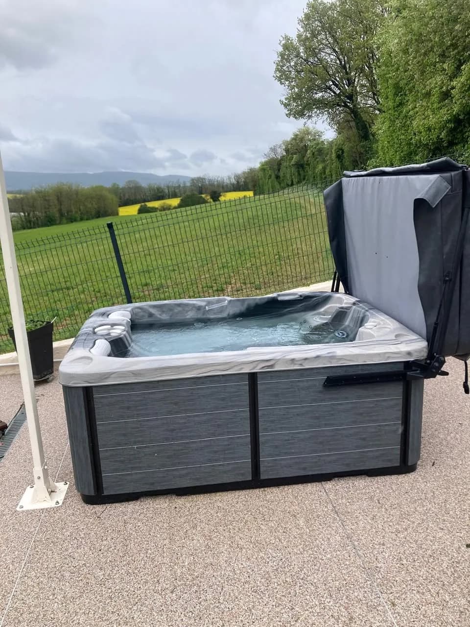Installation d'un spa Tønsberg à Rillieux-la-Pape, sur une terrasse face aux prés, couverture relevée
