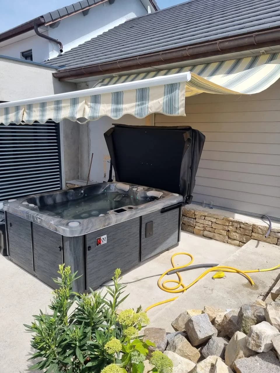Installation d'un spa Tønsberg à Sainte-Colombe, sur une terrasse dallée sous un store banne