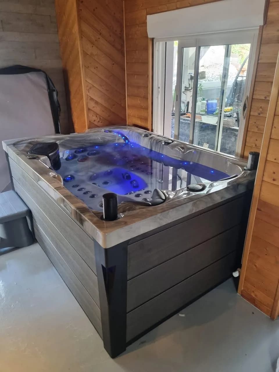 Installation d'un spa Topaz à Dossenheim-sur-Zinsel, dans une véranda en bois, éclairage LED bleu