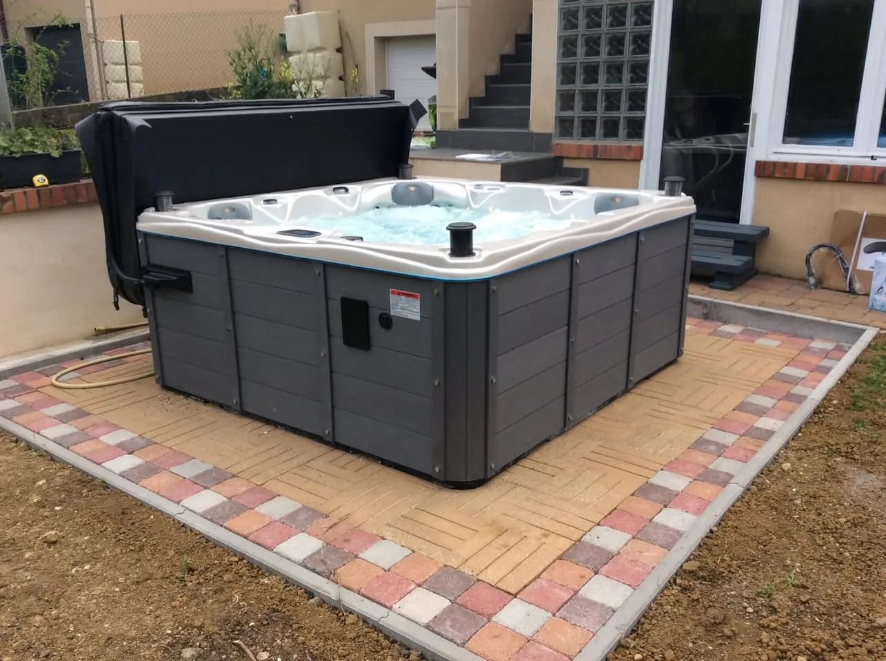 Installation d'un spa Toronto Full option à Lyon, sur une dalle pavée au milieu du jardin