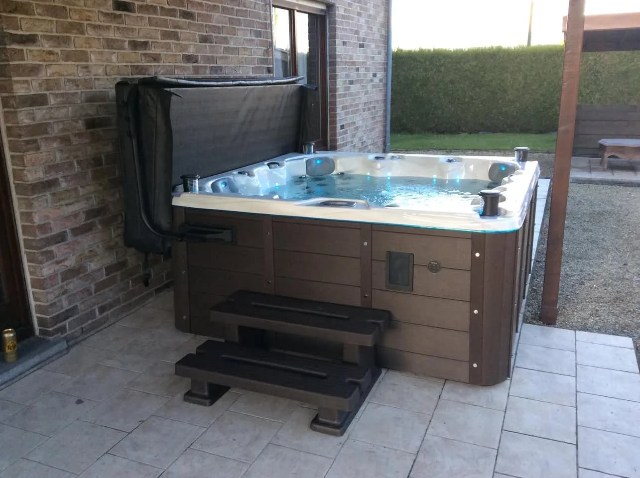 Installation d'un spa Toronto Full option à Tournai, sur une dalle contre un mur de briques, tablier brun