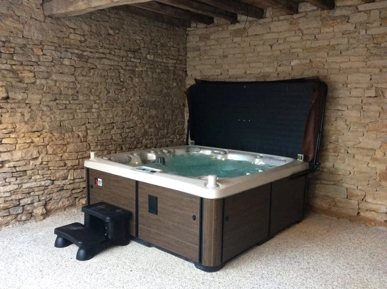 Installation d'un spa Tørrvika Full option, sous un abri contre un mur en pierre