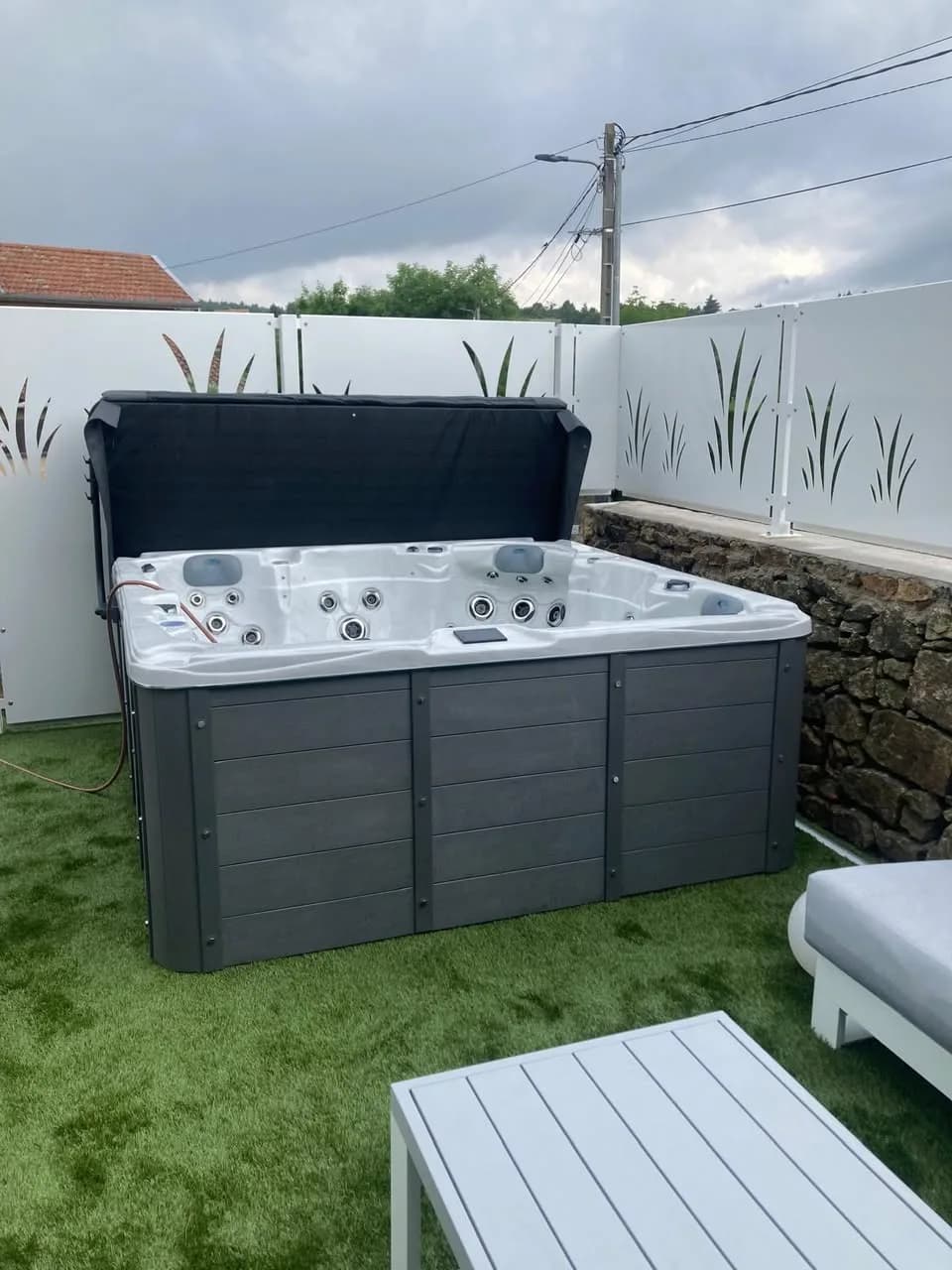 Installation d'un spa Vancouver à Annonay, sur un gazon synthétique devant une clôture