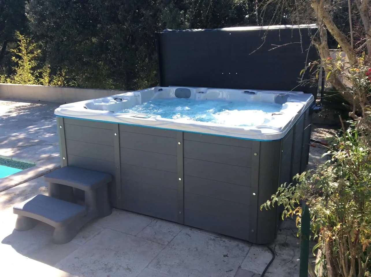 Installation d'un spa Vancouver à Assas, près d'une piscine, lève-couverture