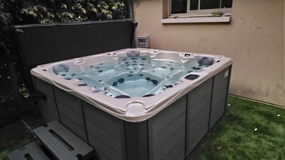 Installation d'un spa Vancouver dans le Nord, sur un gazon synthétique contre la maison