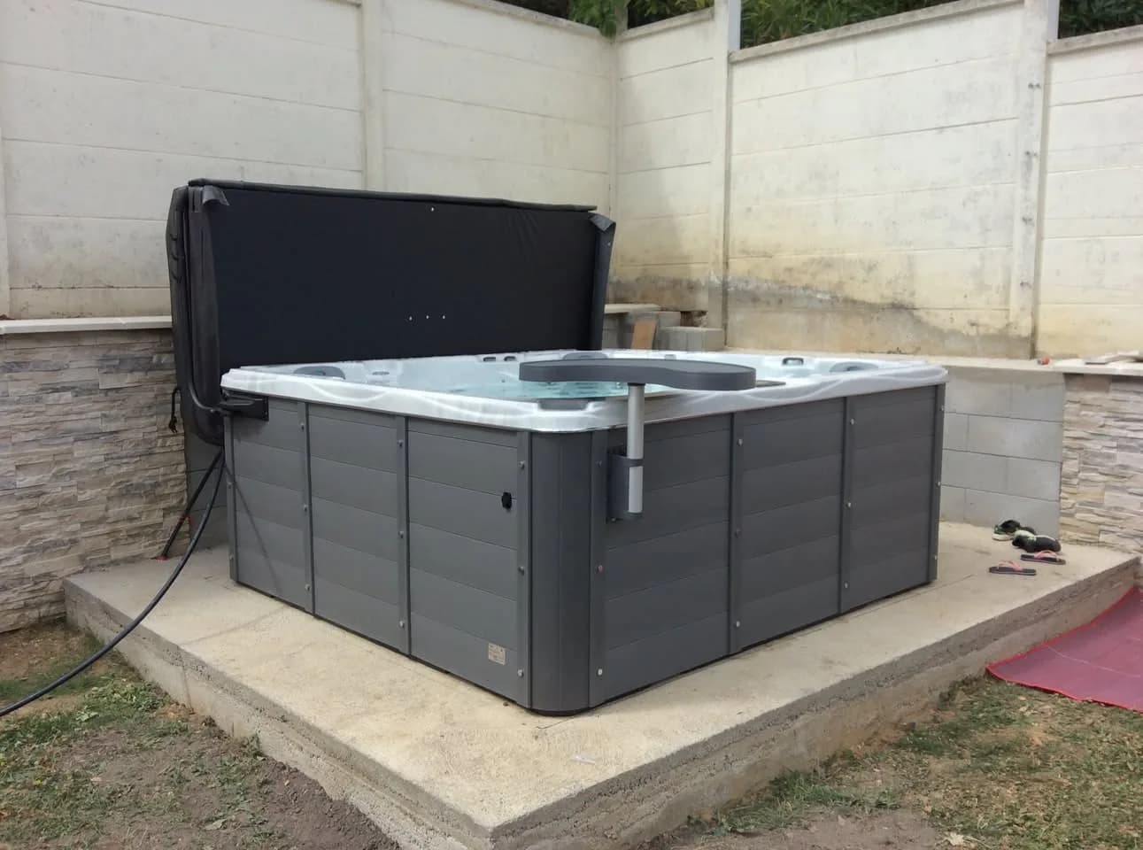 Installation d'un spa Vancouver dans les Ardennes, sur une dalle contre un mur, avec lève-couverture