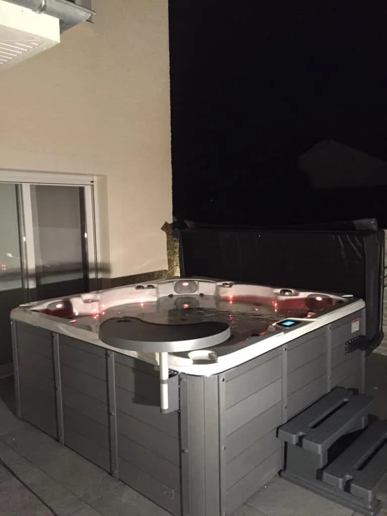 Installation d'un spa Vancouver en Isère, près d'une baie vitrée, marchepied