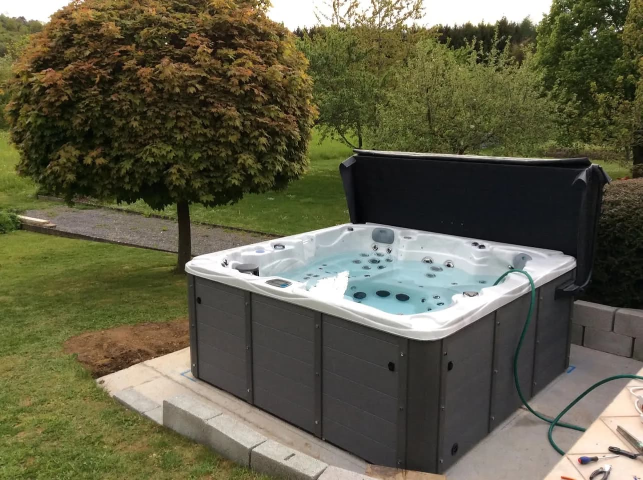 Installation d'un spa Vancouver Full option à Gibet, dans un jardin arboré, lève-couverture