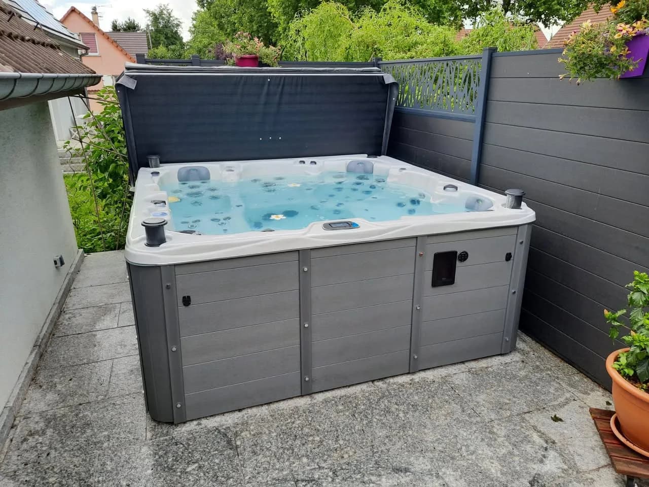 Installation d'un spa Vancouver Full option à Habsheim, sur une dalle devant une palissade grise