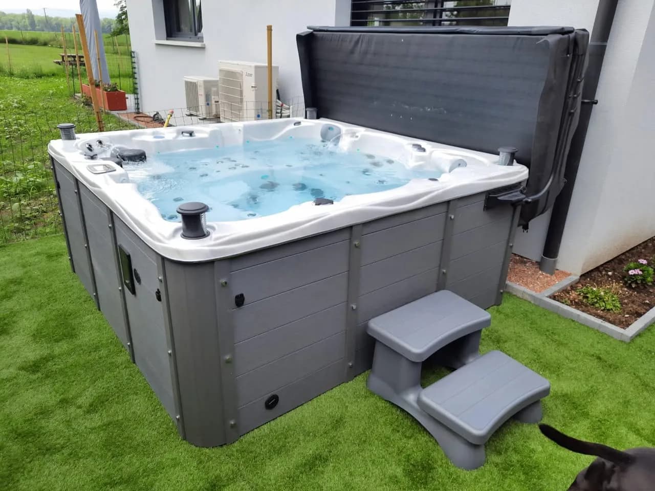 Installation d'un spa Vancouver Full option à Riedwihr, sur un gazon synthétique, lève-couverture et marchepied