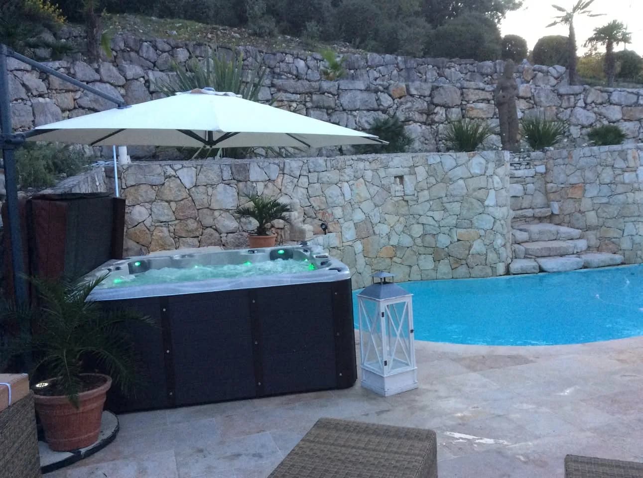 Installation d'un spa Vancouver Full option à Roquefort-les-Pins, au bord d'une piscine, au pied d'un mur en pierre