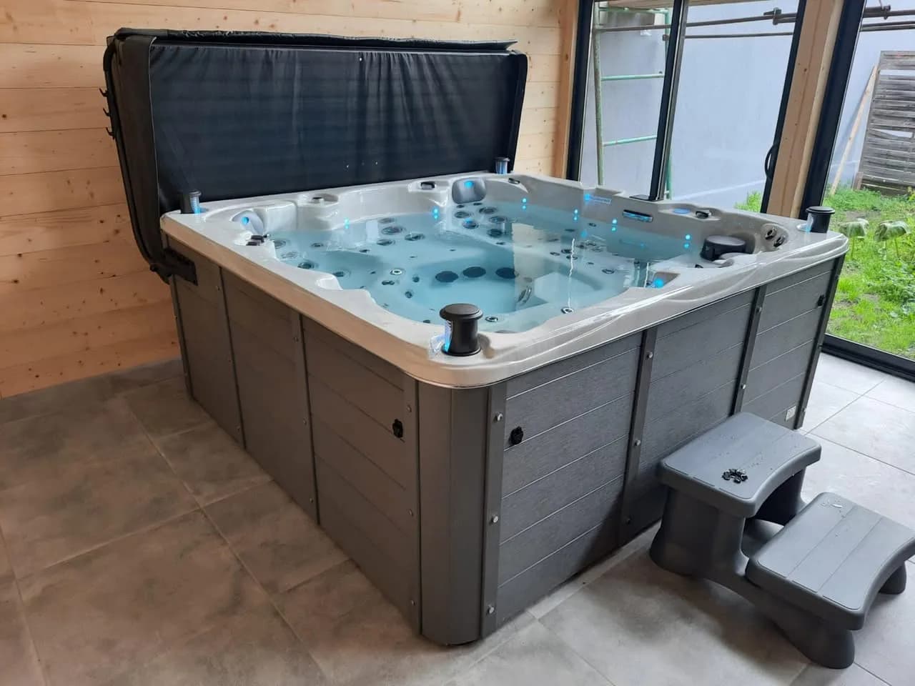 Installation d'un spa Vancouver Full option à Saint-Nabord, sous un abri en bois vitré, marchepied