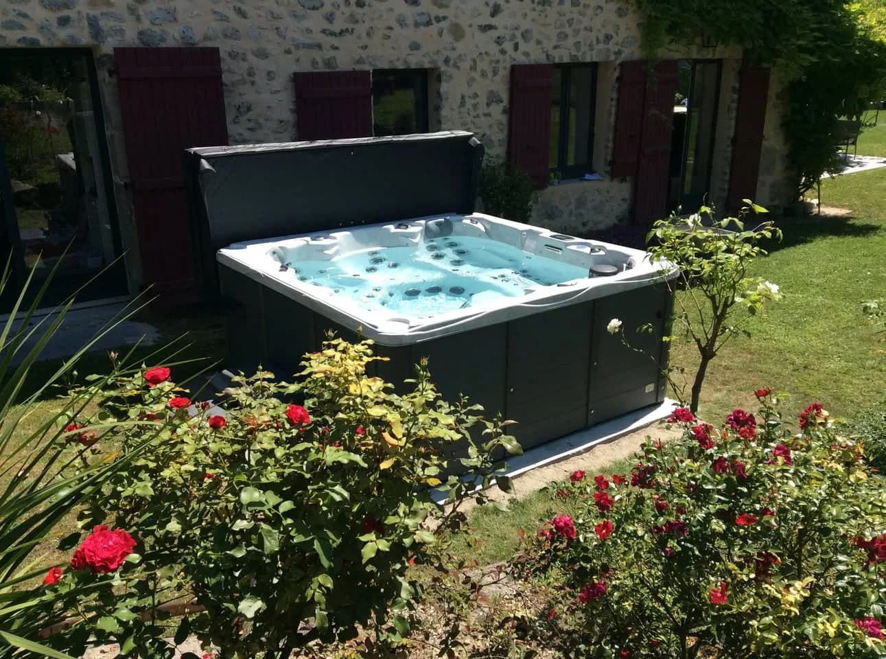 Installation d'un spa Vancouver Full option à Saint-Paul-de-Varces, dans un jardin fleuri devant une maison en pierre