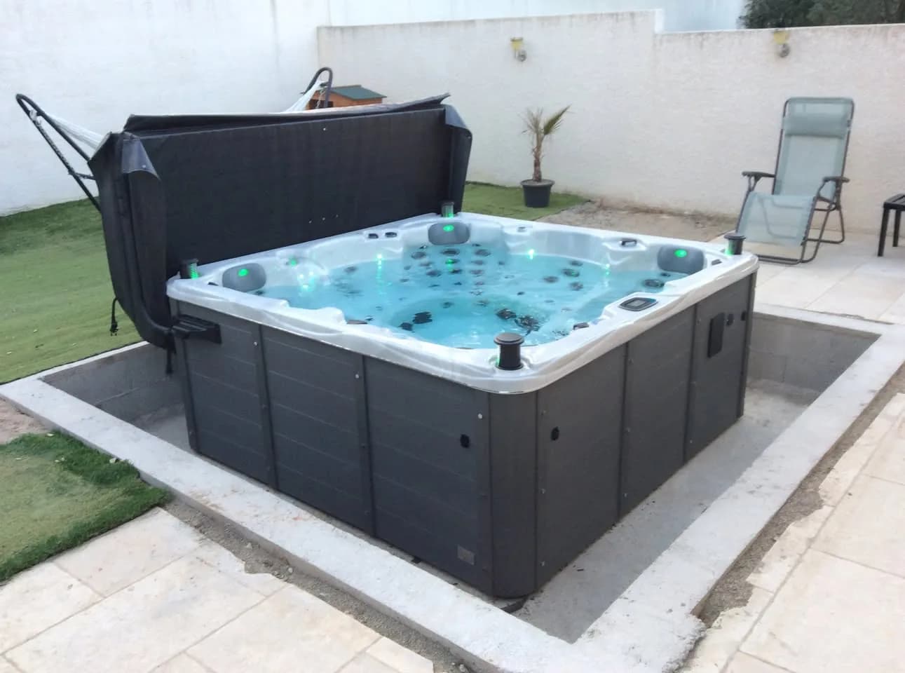 Installation d'un spa Vancouver Full option à Sussargues, sur une dalle dans un jardin, lève-couverture