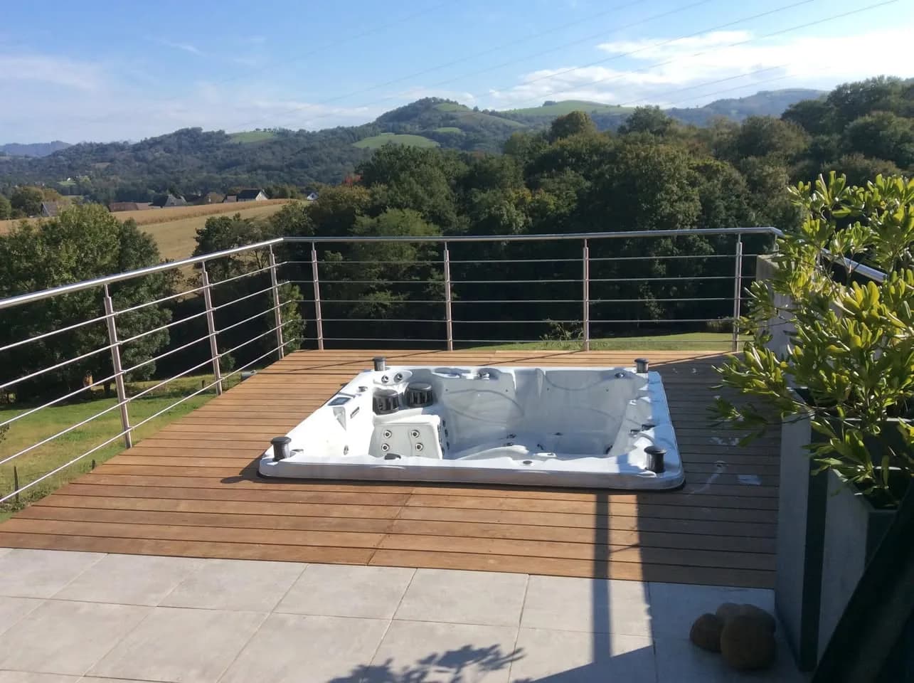 Installation d'un spa Vancouver Full option à Viodos-Abense-de-Bas, encastré dans une terrasse en bois, vue sur les collines